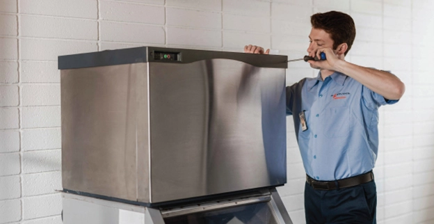 Mr. Appliance service professional working on top of ice machine.