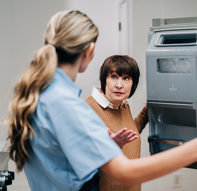 Mr. Appliance service professional inspecting ice maker with customer.