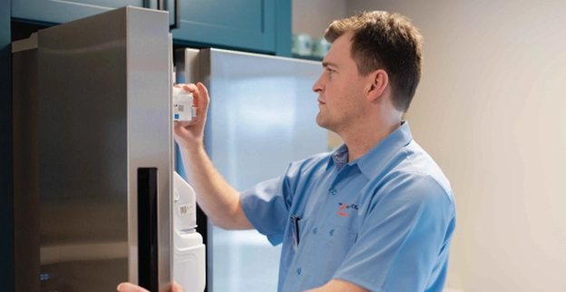 Mr. Appliance service professional inspecting the ice maker of a refrigerator.