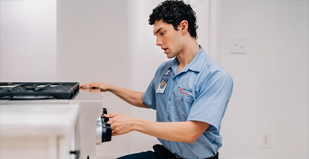 Mr. Appliance service professional turning knob on front of oven.