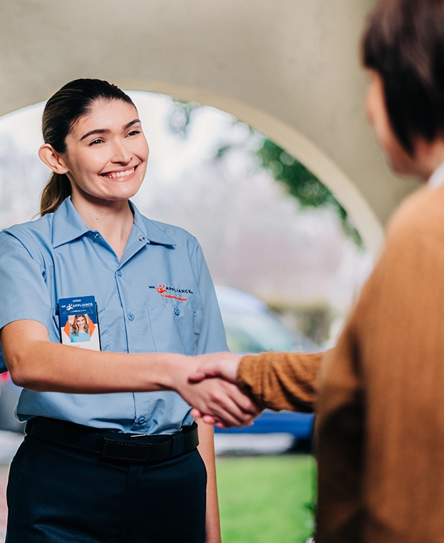 Mr. Appliance service professional smiling at customer at front door.