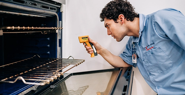 Mr. Appliance service professional reviewing inside of an oven.