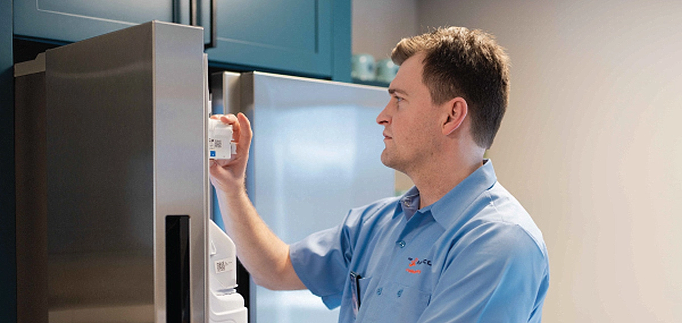 Mr. Appliance service professional inspecting the ice maker of a refrigerator.