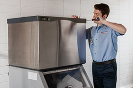 Mr. Appliance service professional working on top of ice machine.