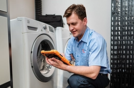 Mr. Appliance service professional reviewing iPad in front of washing machine.