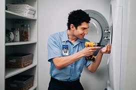 Mr. Appliance service professional smiling as using drill on dryer door.