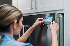 Mr. Appliance service professional applying brand sticker on front of refrigerator.