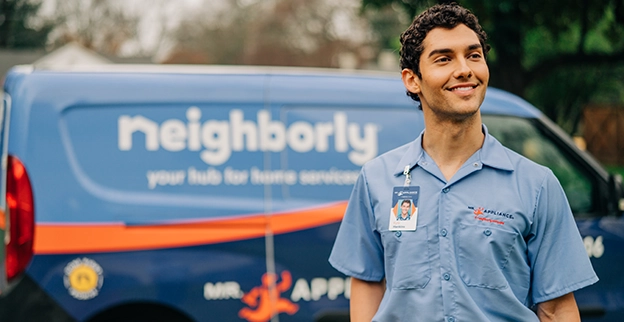 Mr. Appliance service professional smiling in front of branded van.