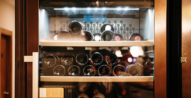 Wine cooler fridge full of bottles of wine.