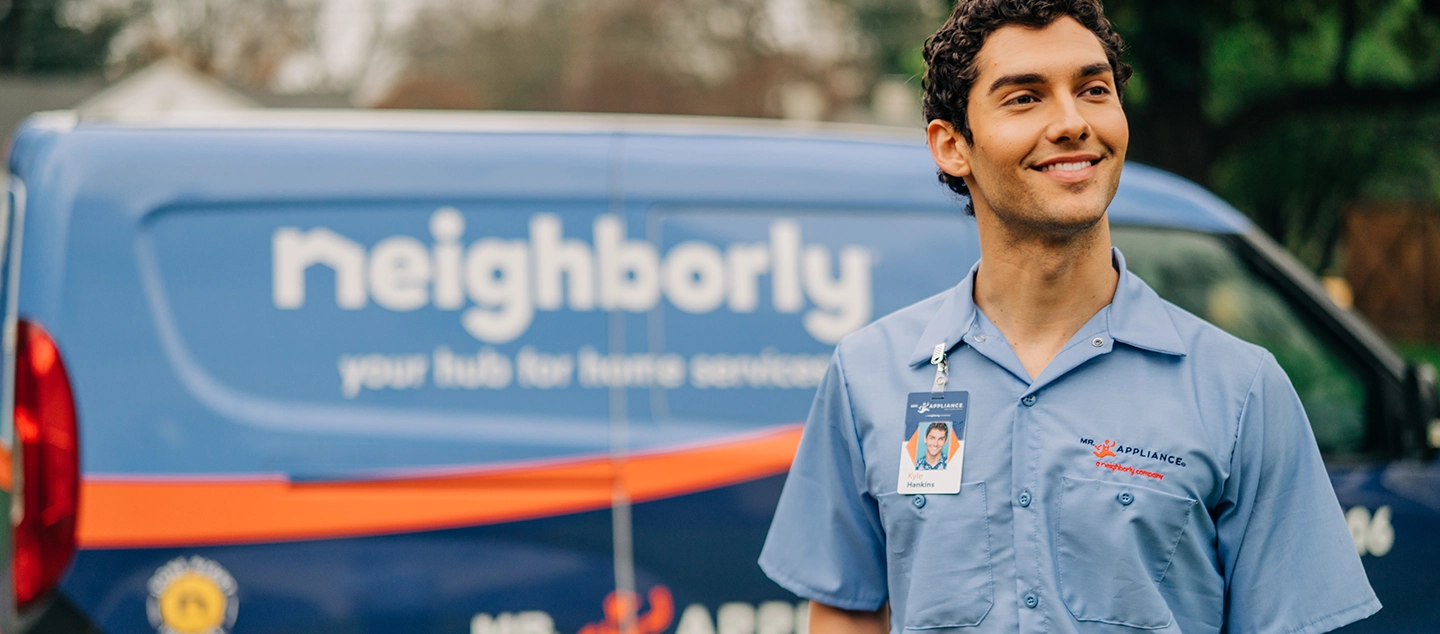 Male tech smiling in front of branded van.