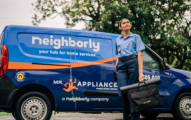 Female Mr. Appliance service technician with tool bag standing in front of branded van.