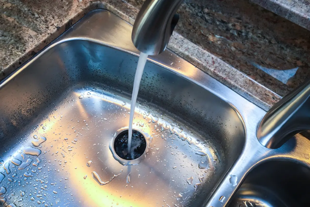 Water running down a kitchen sink with food disposal.