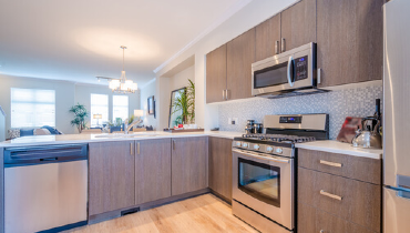 A modern, bright kitchen with driftwood-brown-colored cabinets and stainless-steel appliances.