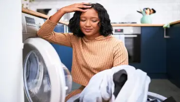  Woman looking frustrated at clothes out of the dryer.