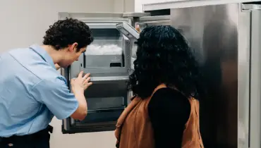 Image of a qualified service professional repairing a leaking refrigerator.