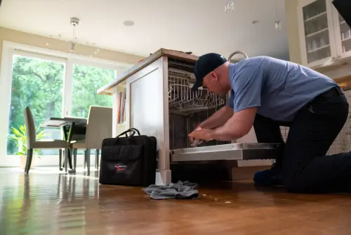 A Mr. Appliance service professional repairing a broken dishwasher.