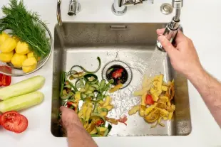 Washing food waste into a kitchen garbage disposal.