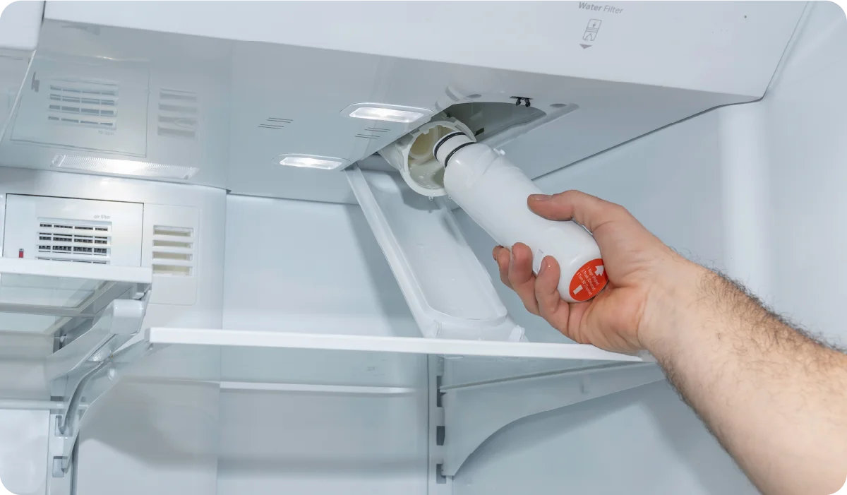 Person changing the water filter inside a fridge.