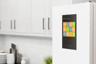 A smart refrigerator with a digital door display in a white, modern kitchen.