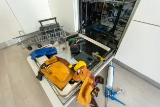 Tools in an open dishwasher for appliance repair.