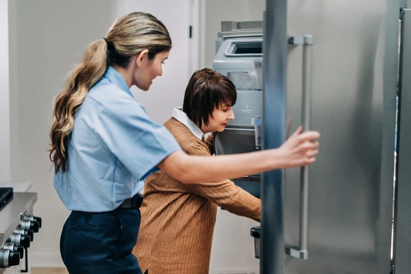 Mr. Appliance service professional and client look at a refrigerator not cooling.