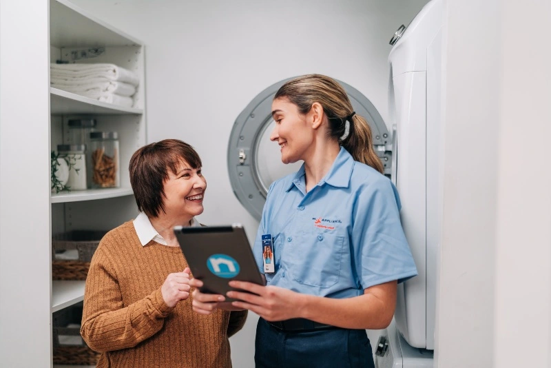 A Mr. Appliance technician showing a customer washer & dryer repair options 