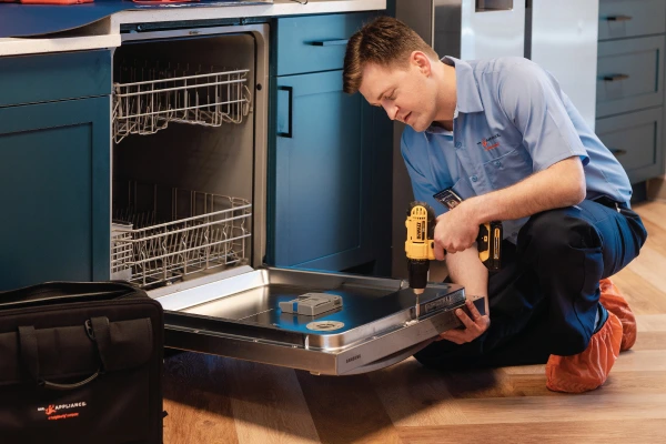 Service professional working on dishwasher.